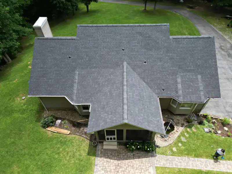 Drone aerial of a ranch-style home with a newly installed dark architectural shingle roof.