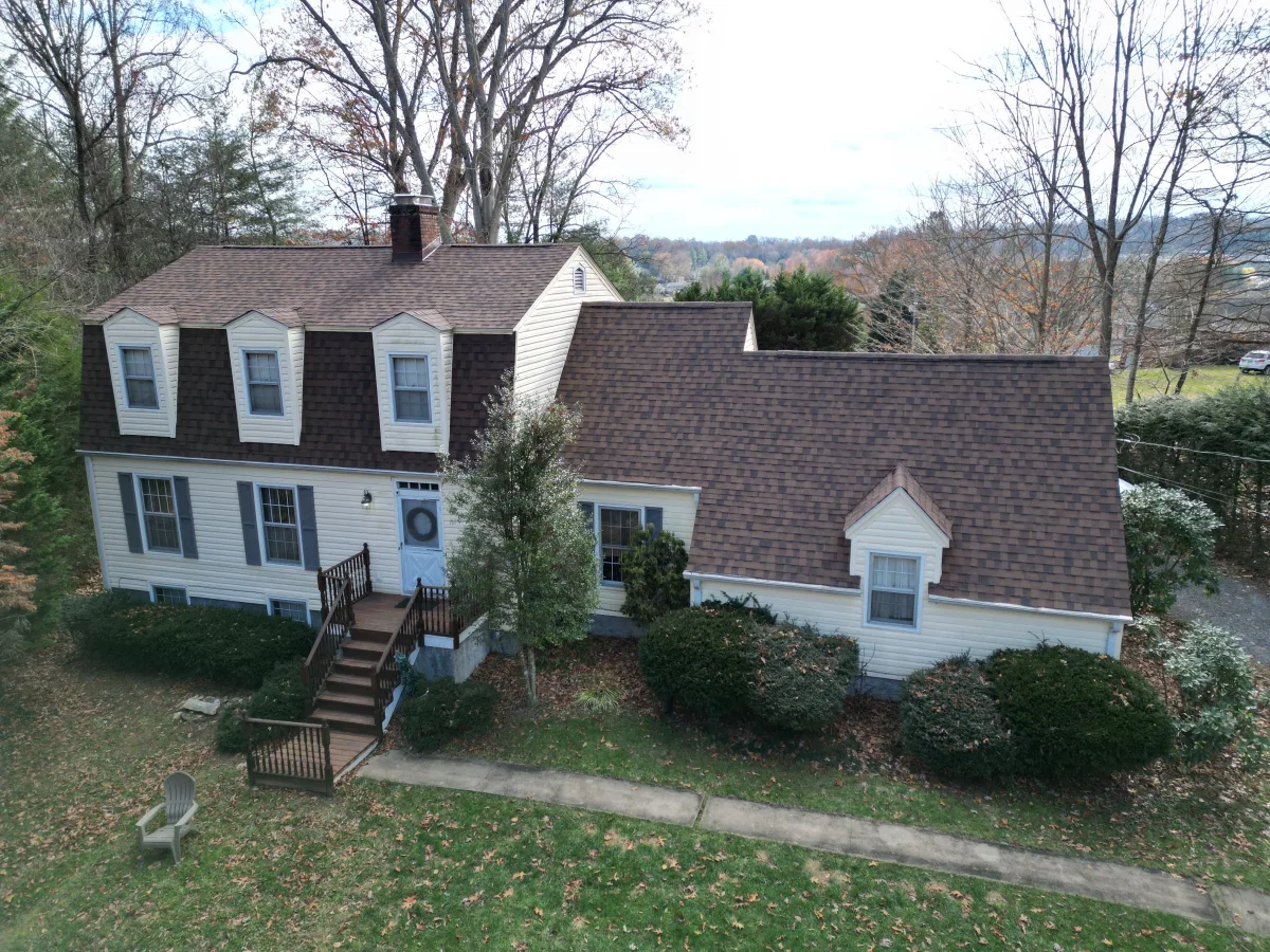 Hickory brown architectural shingles on a gambrel-roof colonial with cream siding — a Palisade Roofing install in East Tennessee.
